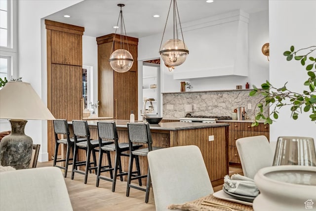 kitchen featuring kitchen peninsula, decorative backsplash, decorative light fixtures, an inviting chandelier, and light hardwood / wood-style floors