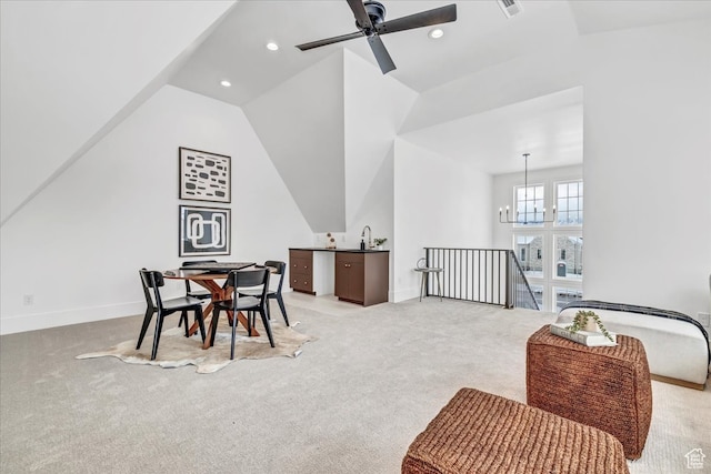 dining area featuring ceiling fan with notable chandelier, light colored carpet, and vaulted ceiling