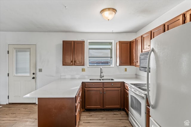 kitchen featuring kitchen peninsula, sink, light hardwood / wood-style floors, and white appliances