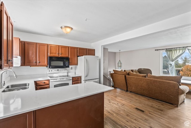 kitchen featuring kitchen peninsula, sink, wood-type flooring, and white appliances