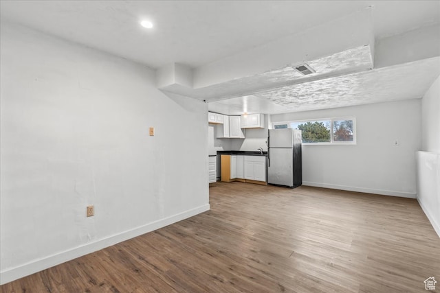 unfurnished living room with light hardwood / wood-style floors and sink