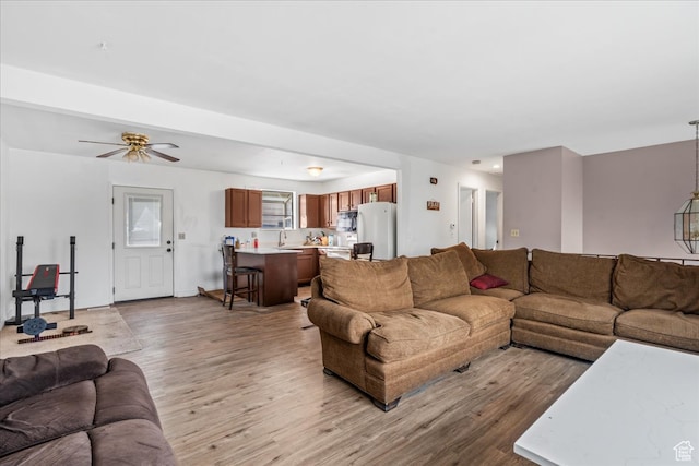 living room with ceiling fan, sink, and light hardwood / wood-style floors