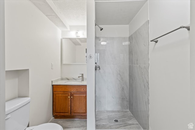bathroom featuring toilet, vanity, a textured ceiling, and tiled shower