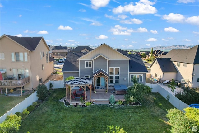 rear view of property featuring a yard, a hot tub, and a deck