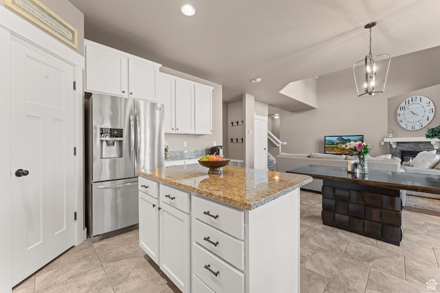 kitchen featuring a center island, stainless steel fridge, white cabinets, and a stone fireplace