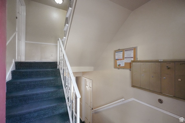 stairs featuring a mail area and lofted ceiling