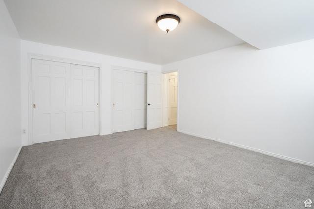 unfurnished bedroom with carpet flooring and multiple closets