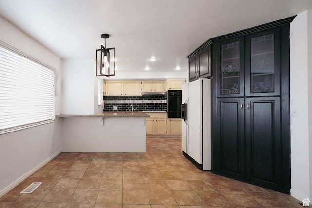 kitchen with white fridge with ice dispenser, kitchen peninsula, cream cabinets, a chandelier, and decorative backsplash