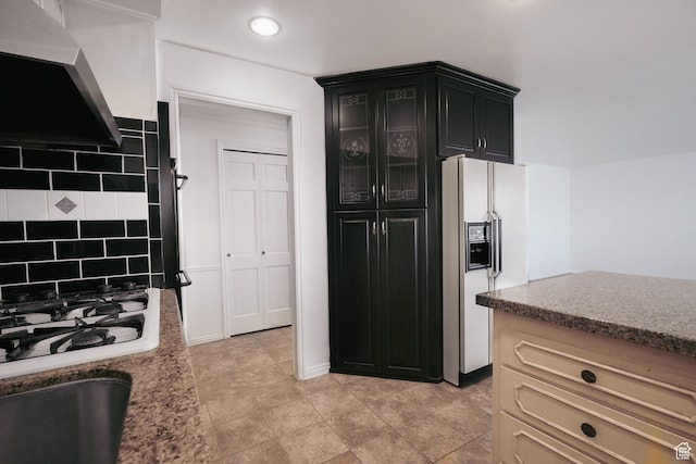 kitchen with white appliances, backsplash, cream cabinets, light tile patterned floors, and extractor fan