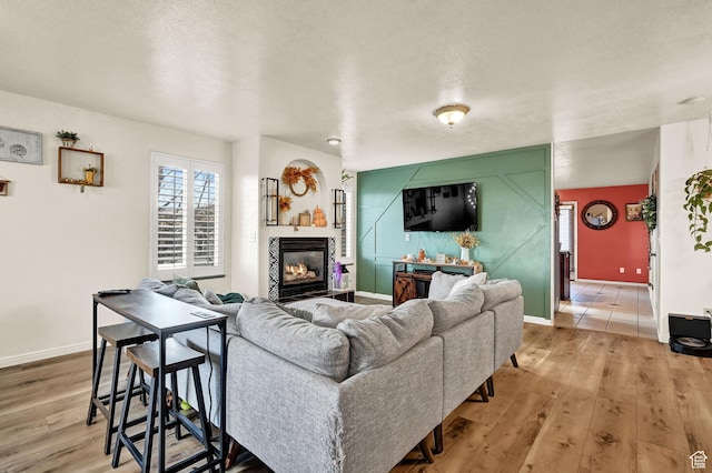 10877 N Wallace Ln E, Tremonton, UT 84337 - living room featuring light wood-type flooring, baseboards, a glass covered fireplace, and a textured ceiling