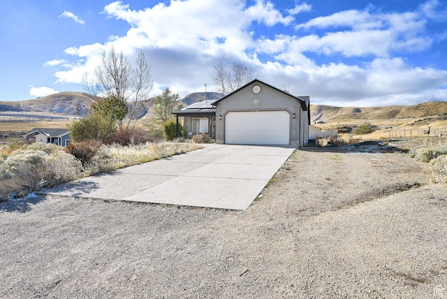 10877 N Wallace Ln E, Tremonton, UT 84337 - view of front of property with concrete driveway, an attached garage, stucco siding, and a mountain view