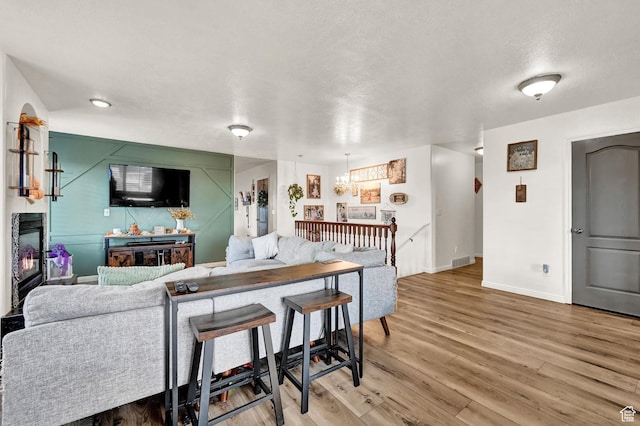 10877 N Wallace Ln E, Tremonton, UT 84337 - living area with light wood-style flooring, baseboards, a chandelier, and a glass covered fireplace