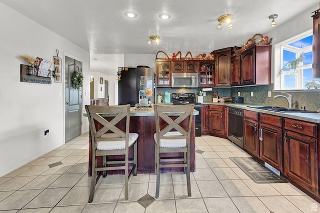 10877 N Wallace Ln E, Tremonton, UT 84337 - kitchen with black appliances, a sink, tasteful backsplash, a kitchen island, and light tile patterned floors