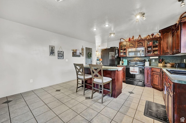 10877 N Wallace Ln E, Tremonton, UT 84337 - kitchen with appliances with stainless steel finishes, a kitchen island, a sink, a breakfast bar, and glass insert cabinets
