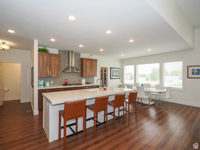 1766 S Degiorgio W, Taylor, UT 84401 - kitchen with a kitchen bar, dark hardwood / wood-style flooring, wall chimney exhaust hood, a center island with sink, and stainless steel gas stovetop