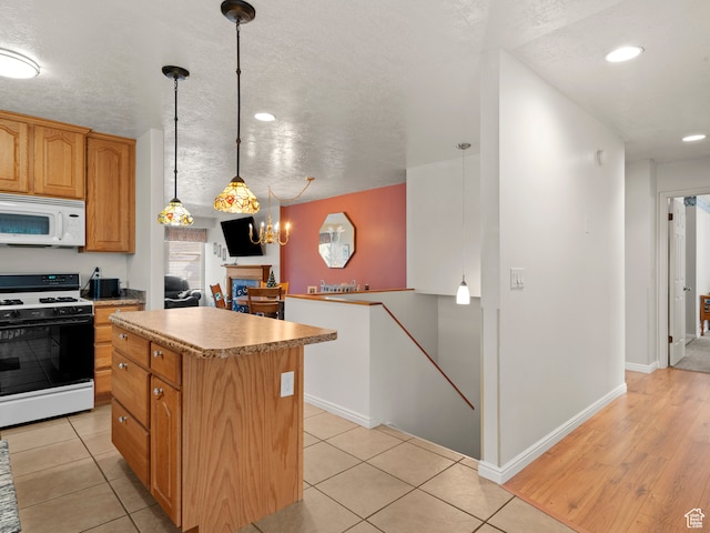3689 W 5215 S, Taylorsville, UT 84129 - kitchen with light countertops, pendant lighting, a kitchen island, light tile patterned floors, and white appliances