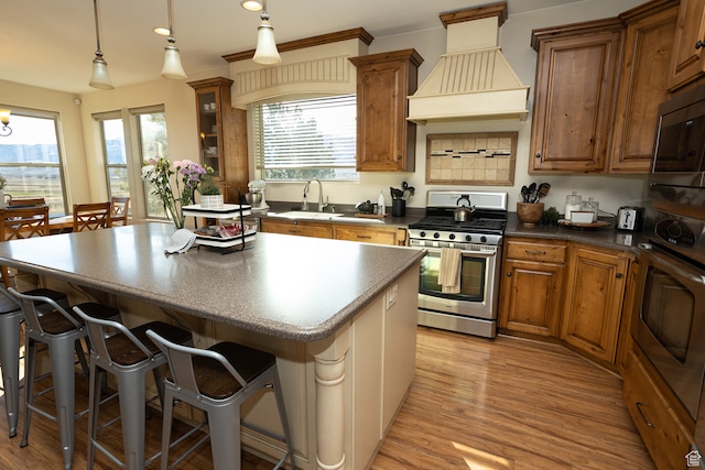 2195 S 1600 W, Richfield, UT 84701 - kitchen featuring pendant lighting, custom exhaust hood, a breakfast bar, light hardwood / wood-style flooring, and stainless steel appliances