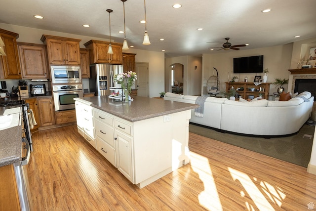 2195 S 1600 W, Richfield, UT 84701 - kitchen with appliances with stainless steel finishes, brown cabinetry, a ceiling fan, open floor plan, and light wood-style flooring