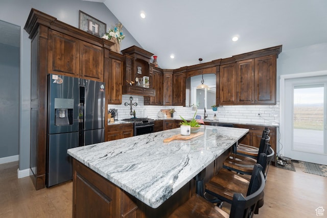 5361 N 4500 E, Roosevelt, UT 84066 - kitchen with appliances with stainless steel finishes, vaulted ceiling, tasteful backsplash, light stone counters, and light wood finished floors