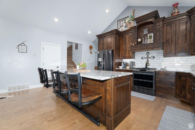 5361 N 4500 E, Roosevelt, UT 84066 - kitchen with appliances with stainless steel finishes, vaulted ceiling, a kitchen island, light stone counters, and backsplash