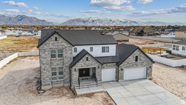 2118 N Snowy Crane Dr, Clinton, UT 84015 - view of front of home with stone siding, a mountain view, a garage, driveway, and a shingled roof