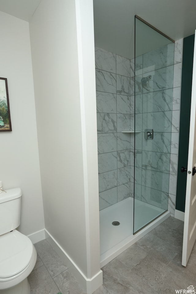 bathroom with a tile shower and toilet