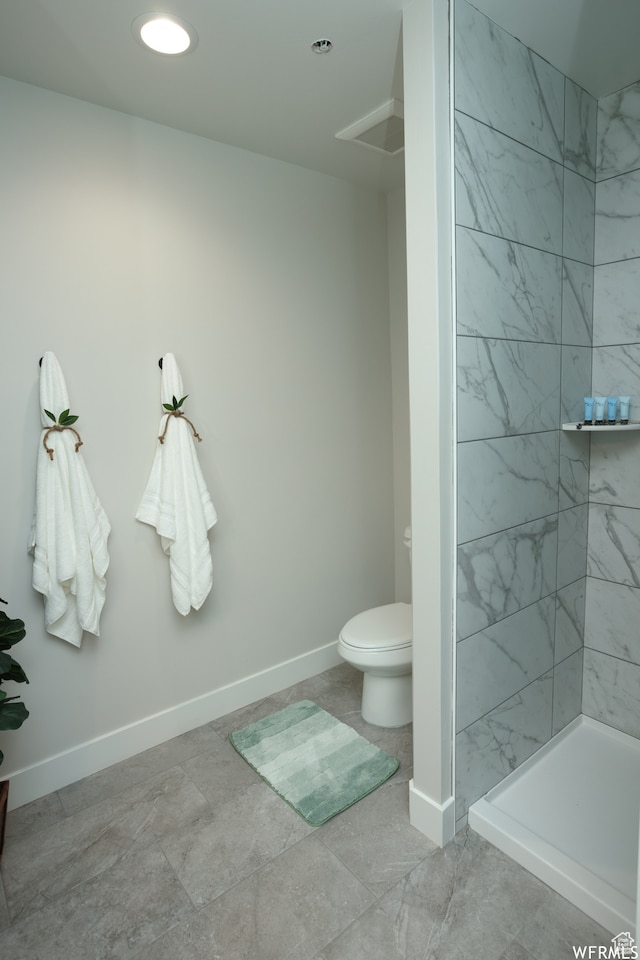 bathroom with a tile shower and toilet