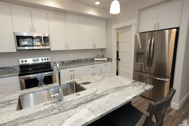 kitchen featuring light stone counters, dark hardwood / wood-style flooring, stainless steel appliances, and decorative light fixtures
