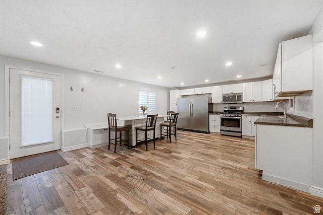 758 W Cedar View Dr, Saratoga Springs, UT 84045 - kitchen featuring appliances with stainless steel finishes, light wood-type flooring, dark countertops, white cabinetry, and recessed lighting
