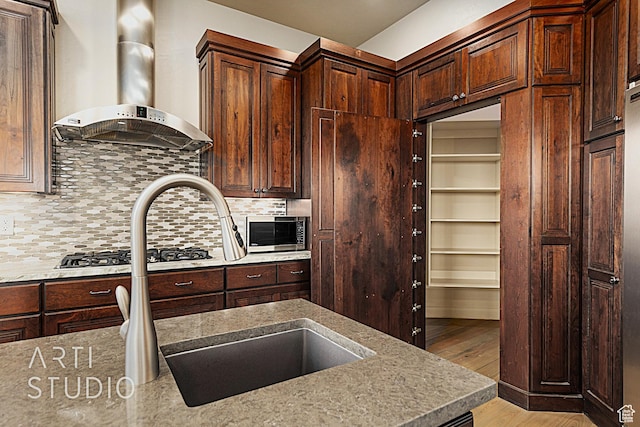 kitchen with sink, backsplash, light hardwood / wood-style floors, and wall chimney exhaust hood