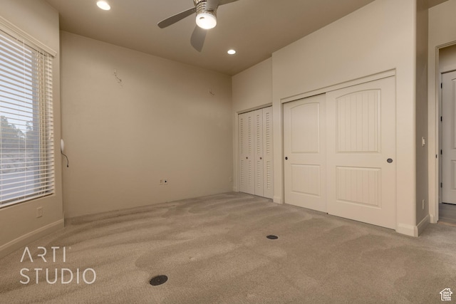 unfurnished bedroom with multiple windows, two closets, carpet floors, and ceiling fan
