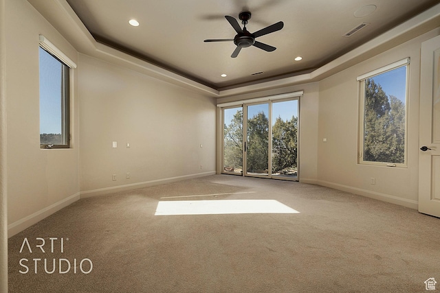 unfurnished room with light colored carpet, ceiling fan, and a tray ceiling