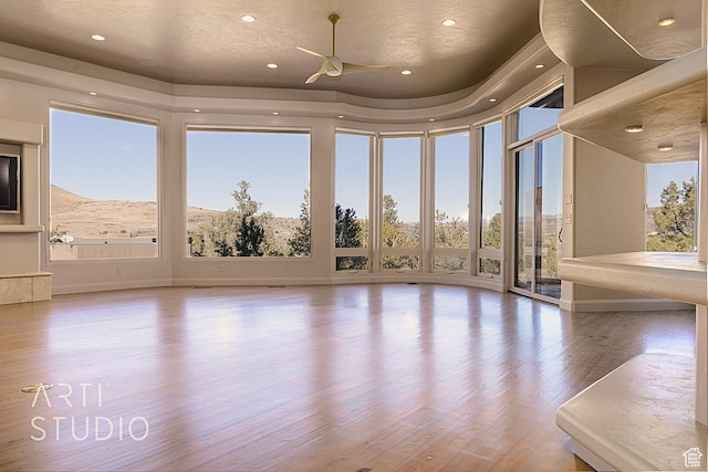 unfurnished room featuring floor to ceiling windows, ceiling fan, and light wood-type flooring