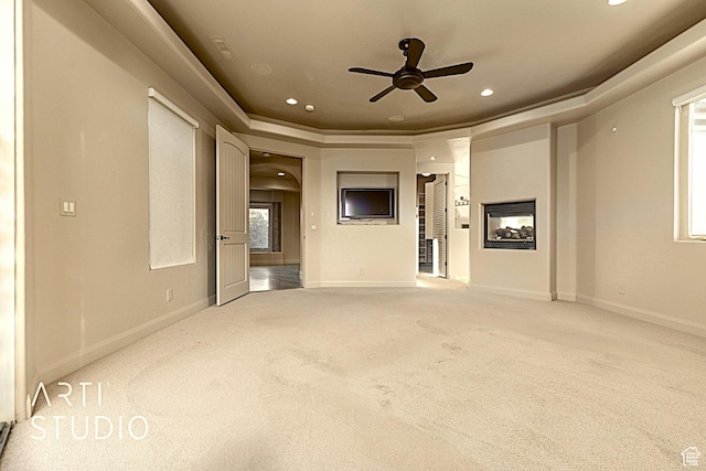carpeted spare room featuring ceiling fan, a multi sided fireplace, and a raised ceiling