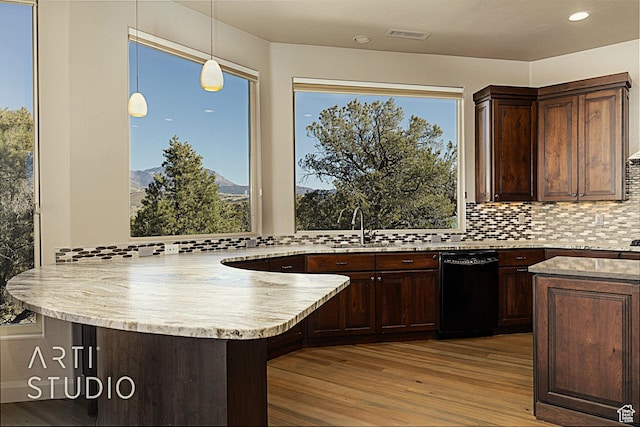 kitchen with a breakfast bar, decorative light fixtures, backsplash, kitchen peninsula, and light wood-type flooring