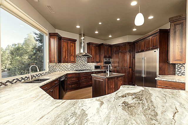 kitchen with decorative light fixtures, sink, backsplash, stainless steel appliances, and wall chimney range hood