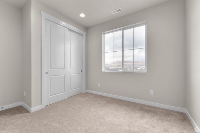 unfurnished bedroom featuring light carpet and a closet