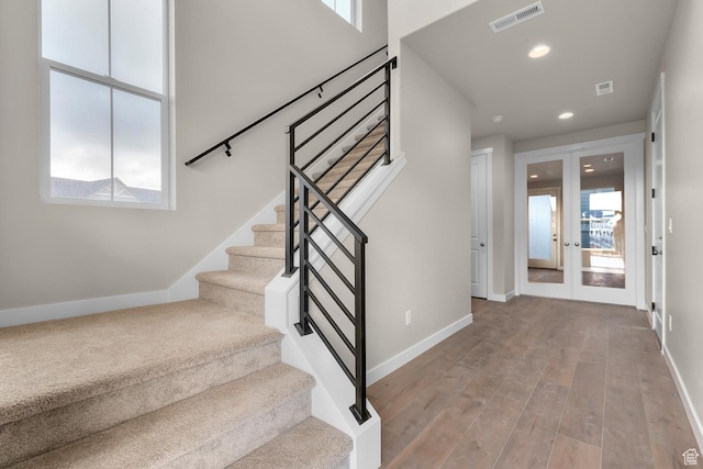 stairs with hardwood / wood-style floors and french doors