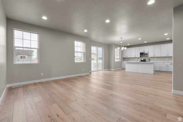 2616 N 3020 W, Clinton, UT 84015 - unfurnished living room with sink, plenty of natural light, a textured ceiling, and light hardwood / wood-style flooring