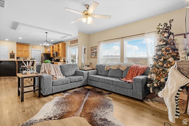 living room featuring light hardwood / wood-style floors and ceiling fan with notable chandelier