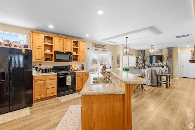 kitchen with sink, light hardwood / wood-style floors, decorative light fixtures, black appliances, and ceiling fan with notable chandelier
