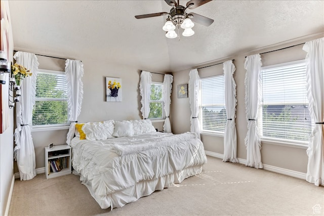 carpeted bedroom with baseboards, ceiling fan, and a textured ceiling