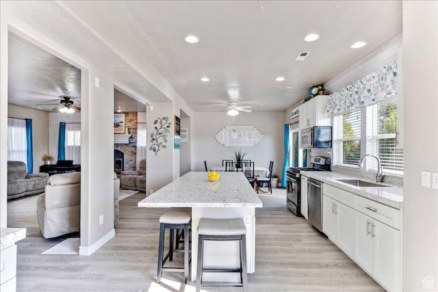 4068 S Schooner Dr, Saratoga Springs, UT 84045 - kitchen with a ceiling fan, a sink, stainless steel appliances, a fireplace, and recessed lighting