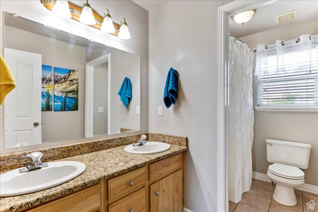 bathroom with toilet, double vanity, a sink, and tile patterned floors