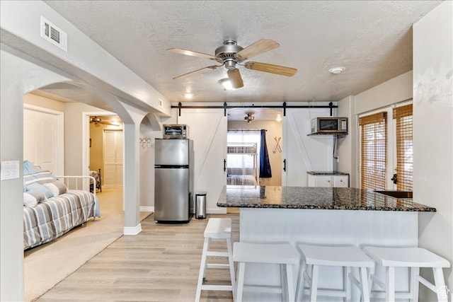 kitchen featuring a barn door, a ceiling fan, visible vents, arched walkways, and appliances with stainless steel finishes