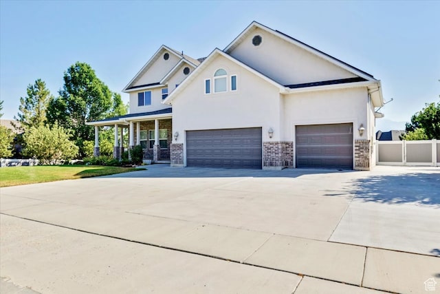 view of front of home with a porch, driveway, brick siding, stucco siding, and fence