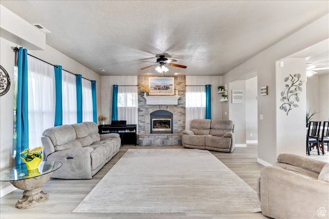 living room with baseboards, wood finished floors, ceiling fan, and a fireplace