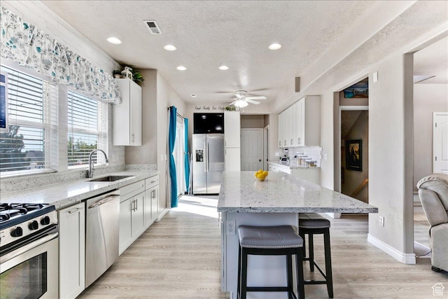 4068 S Schooner Dr, Saratoga Springs, UT 84045 - kitchen featuring a sink, stainless steel appliances, a center island, decorative backsplash, and light stone countertops