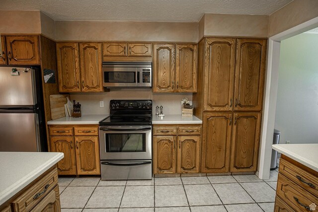 148 S Sunnybrook Dr, Salina, UT 84654 - kitchen with appliances with stainless steel finishes, brown cabinetry, light countertops, light tile patterned floors, and a textured ceiling