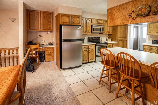 148 S Sunnybrook Dr, Salina, UT 84654 - kitchen featuring appliances with stainless steel finishes, light countertops, brown cabinetry, and a textured ceiling